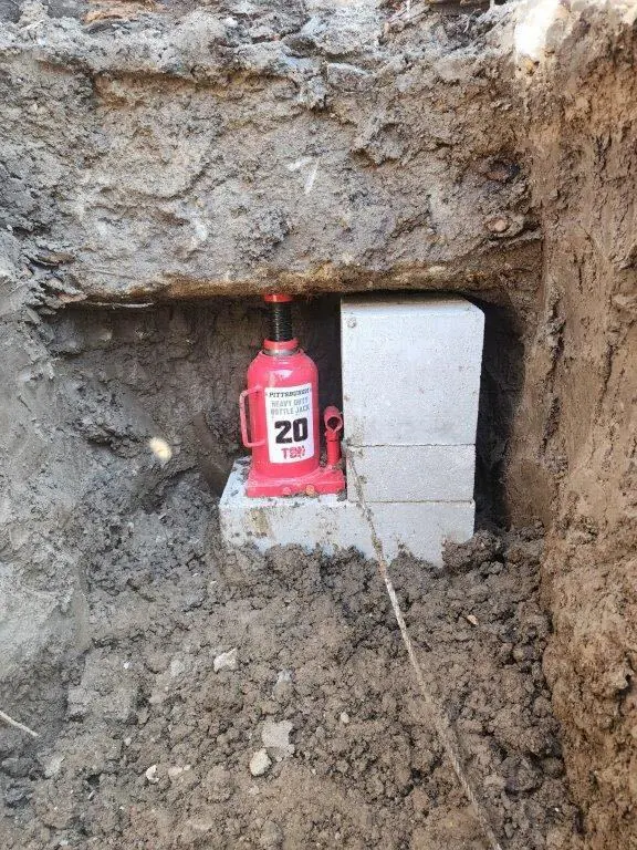 Hydraulic jack and concrete blocks in a foundation access hole