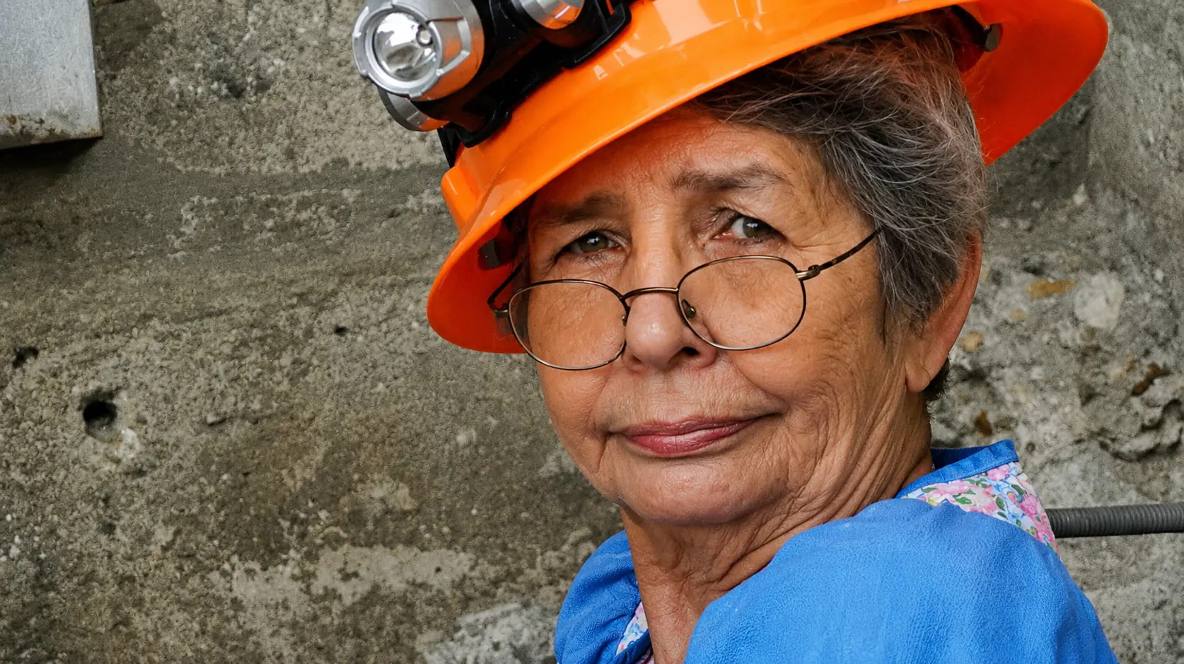 Older woman wearing an orange hard hat and glasses